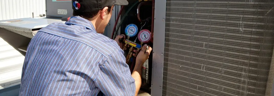 HVAC technician servicing a condenser unit in Rock Island