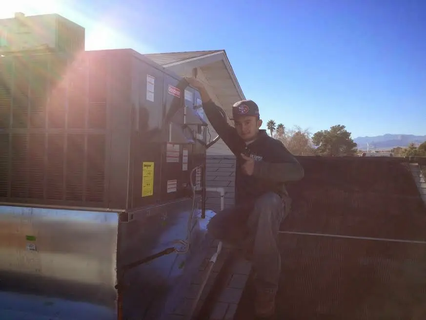 HVAC technician performing AC Tune-Up on a rooftop unit in Rock Island